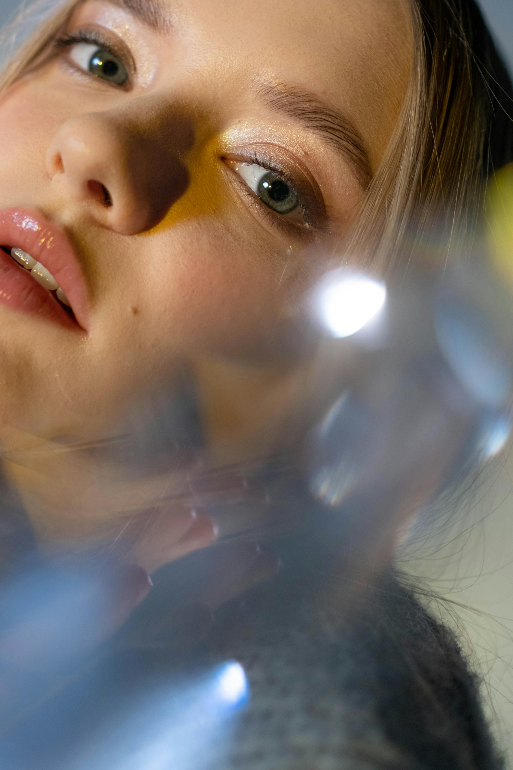 A close-up portrait of a woman with prism effects creating an artistic refraction illusion.